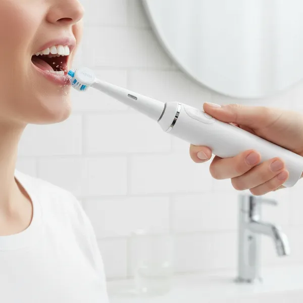 Close-up of a person using an electric toothbrush, showing proper brushing technique for oral health.
