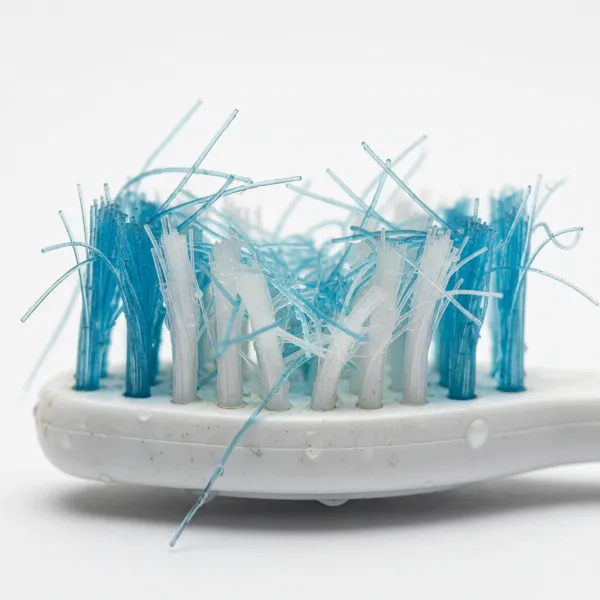 Close-up of a toothbrush with badly splayed and worn-out bristles, indicating aggressive brushing habits.